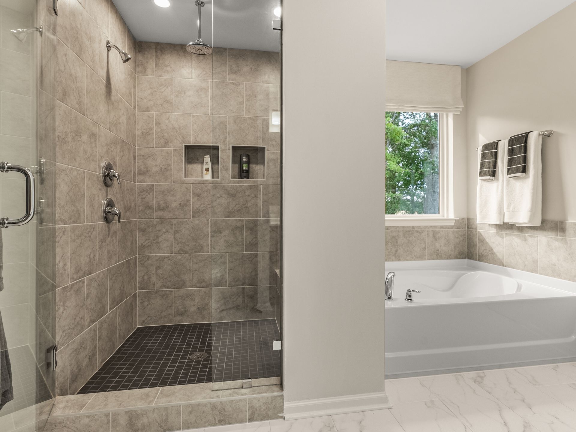 A bathroom with a walk in shower , tub and window.