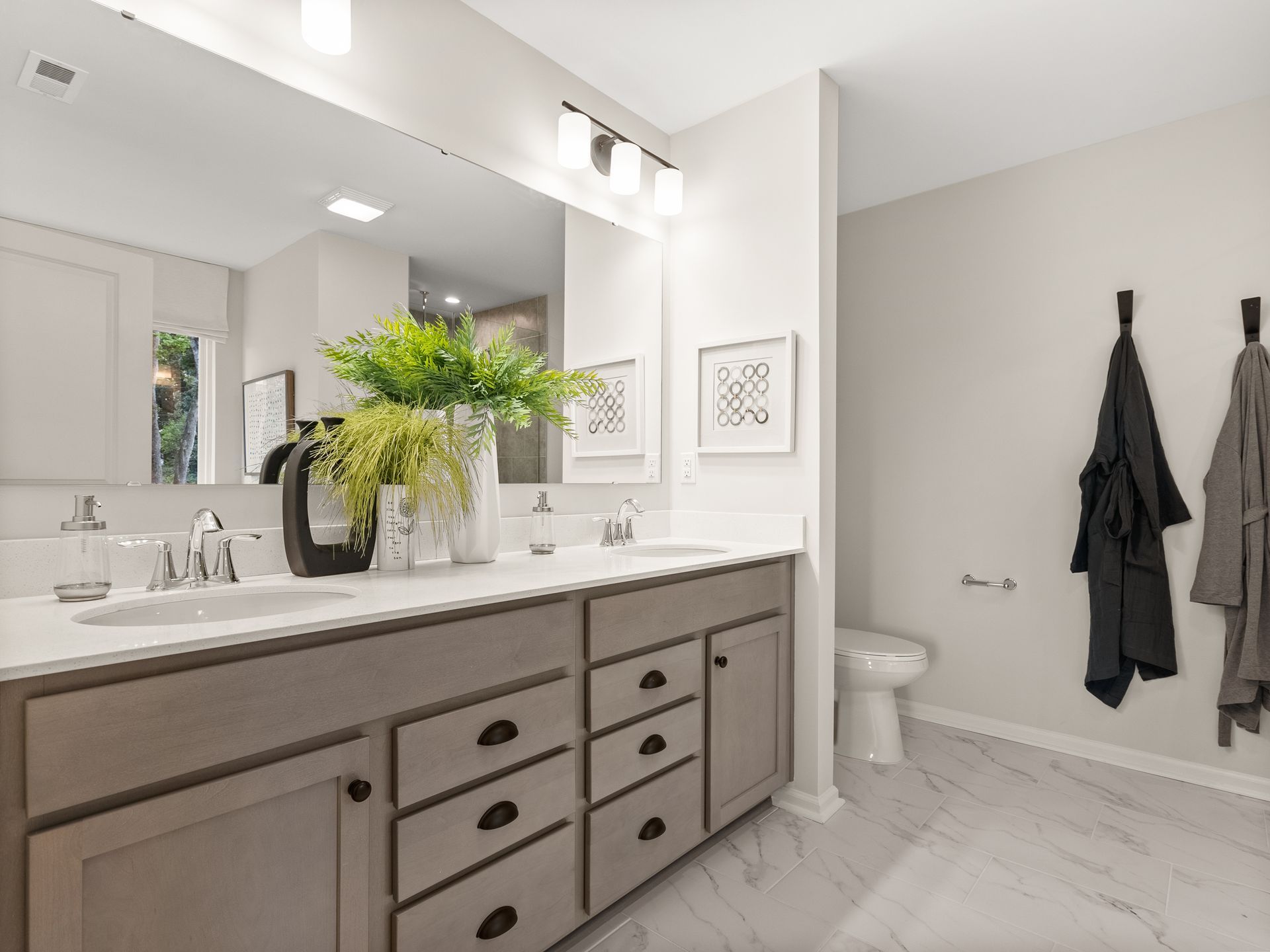 A bathroom with two sinks , a toilet , and a large mirror.