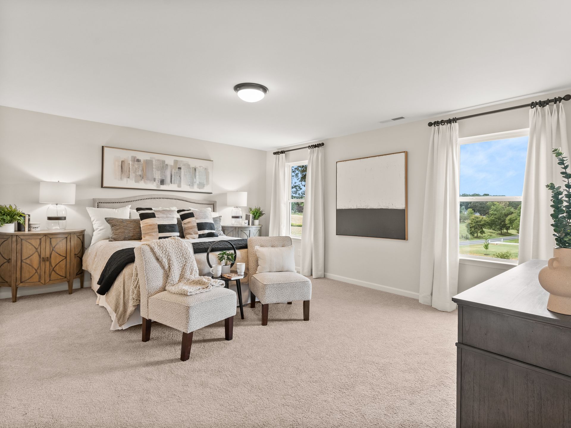 A bedroom with a bed , chairs , dresser and window.