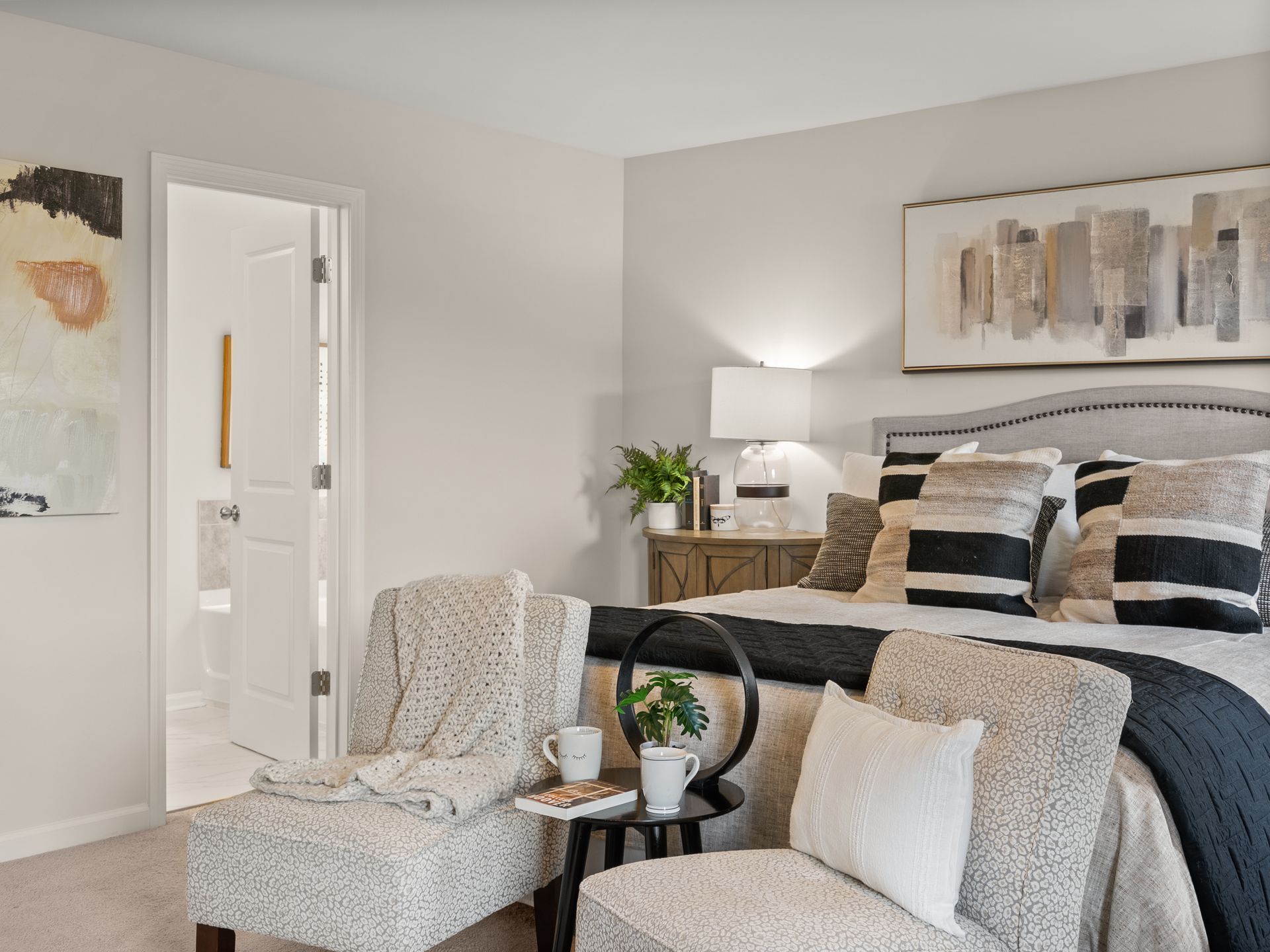 A bedroom with a bed , chairs , a table and a painting on the wall.