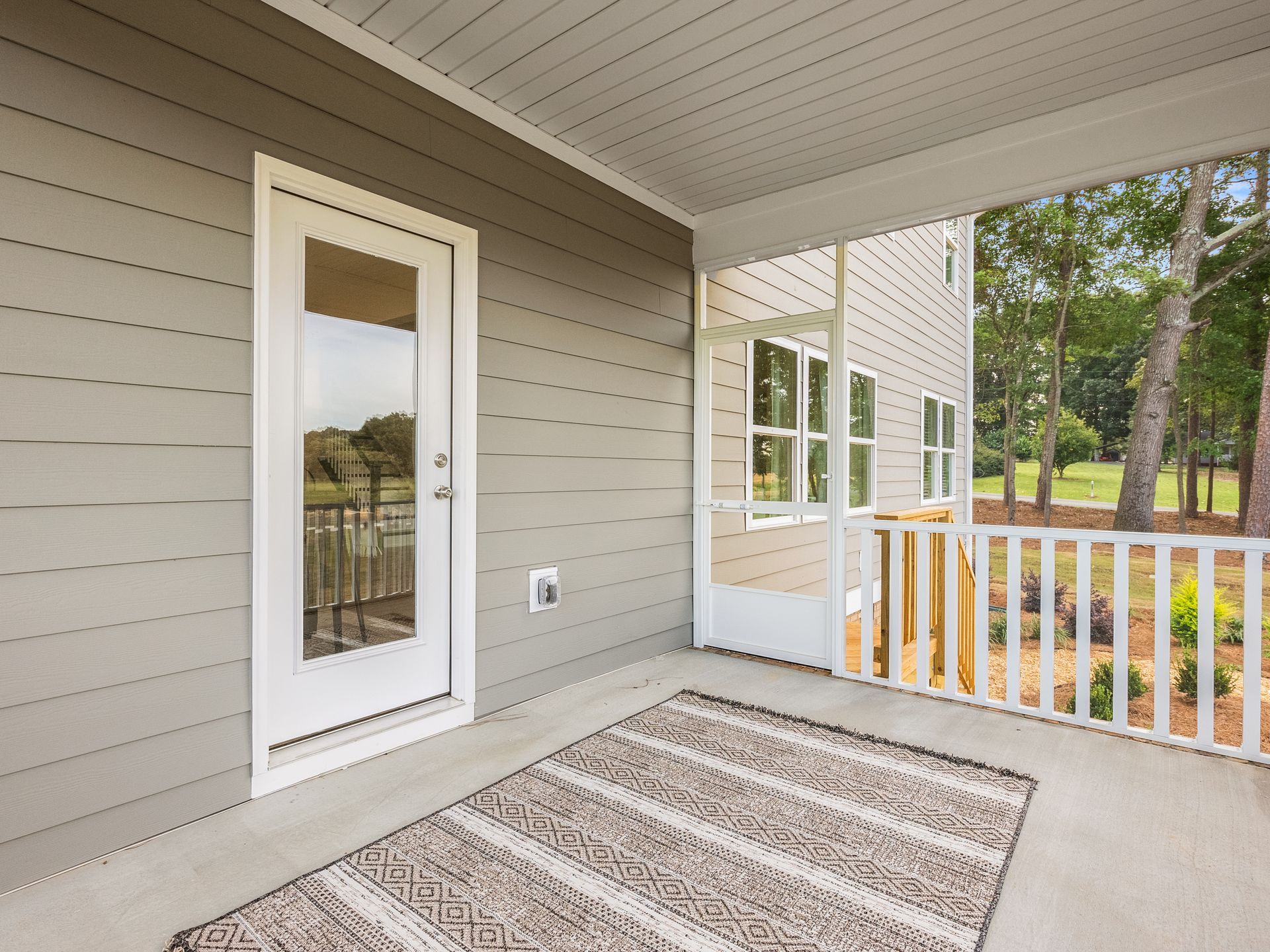 A porch with a rug and a door in a house.