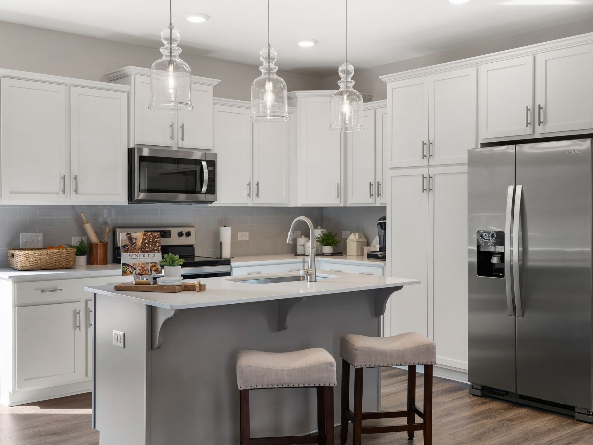 A kitchen with white cabinets , stainless steel appliances , and a large island.
