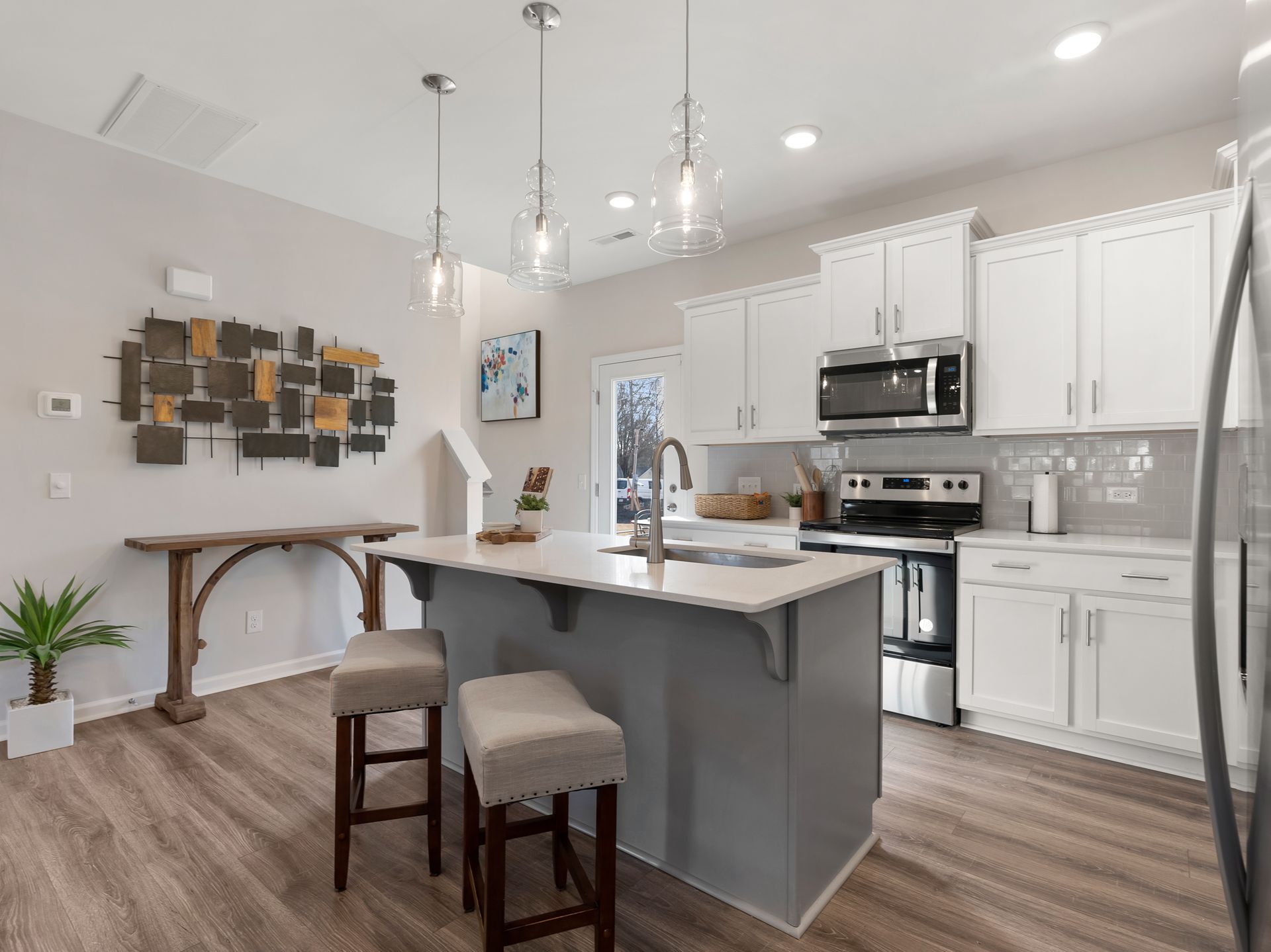 A kitchen with white cabinets , stainless steel appliances , a large island and stools.