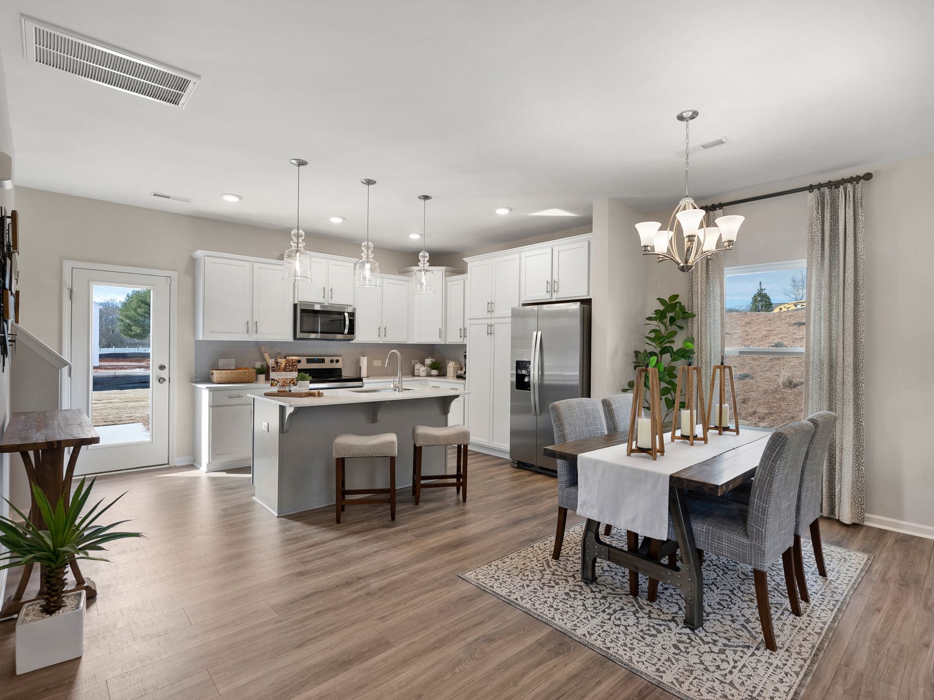 A kitchen and dining room in a model home with a table and chairs.