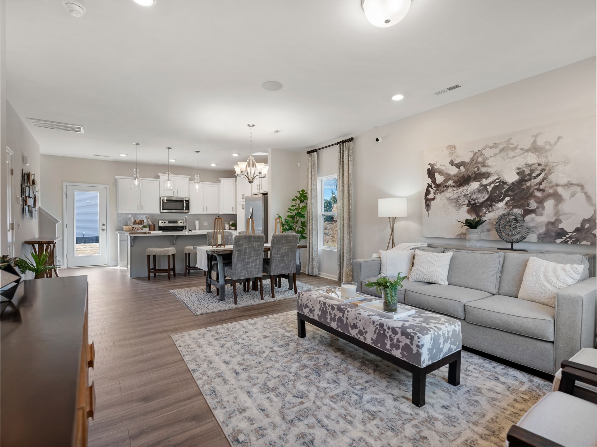 A living room with a couch , coffee table , chairs and a painting on the wall.