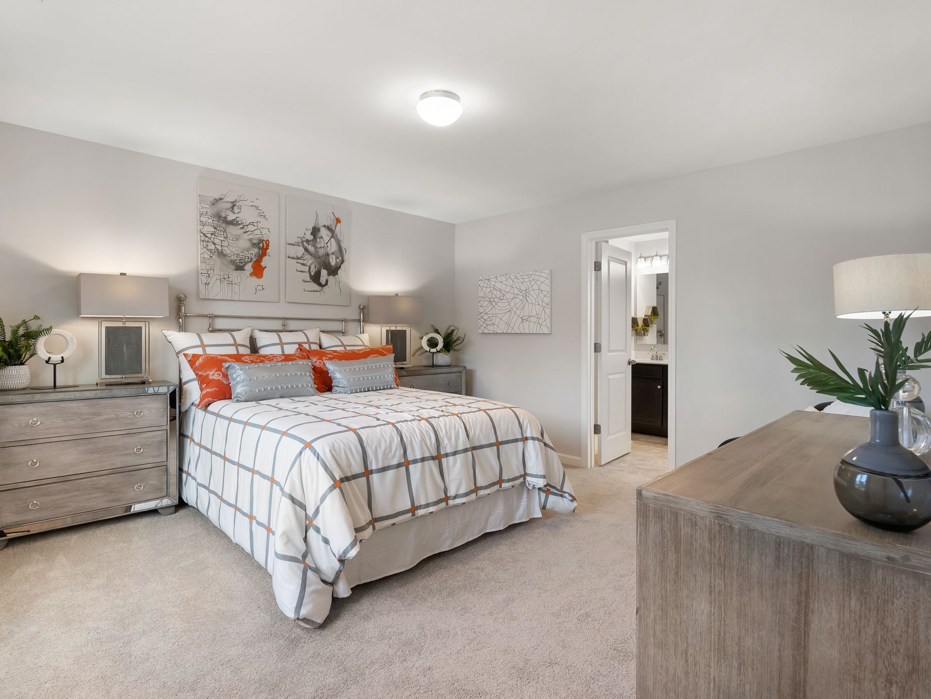 A bedroom with a bed , dresser , nightstand and lamps.
