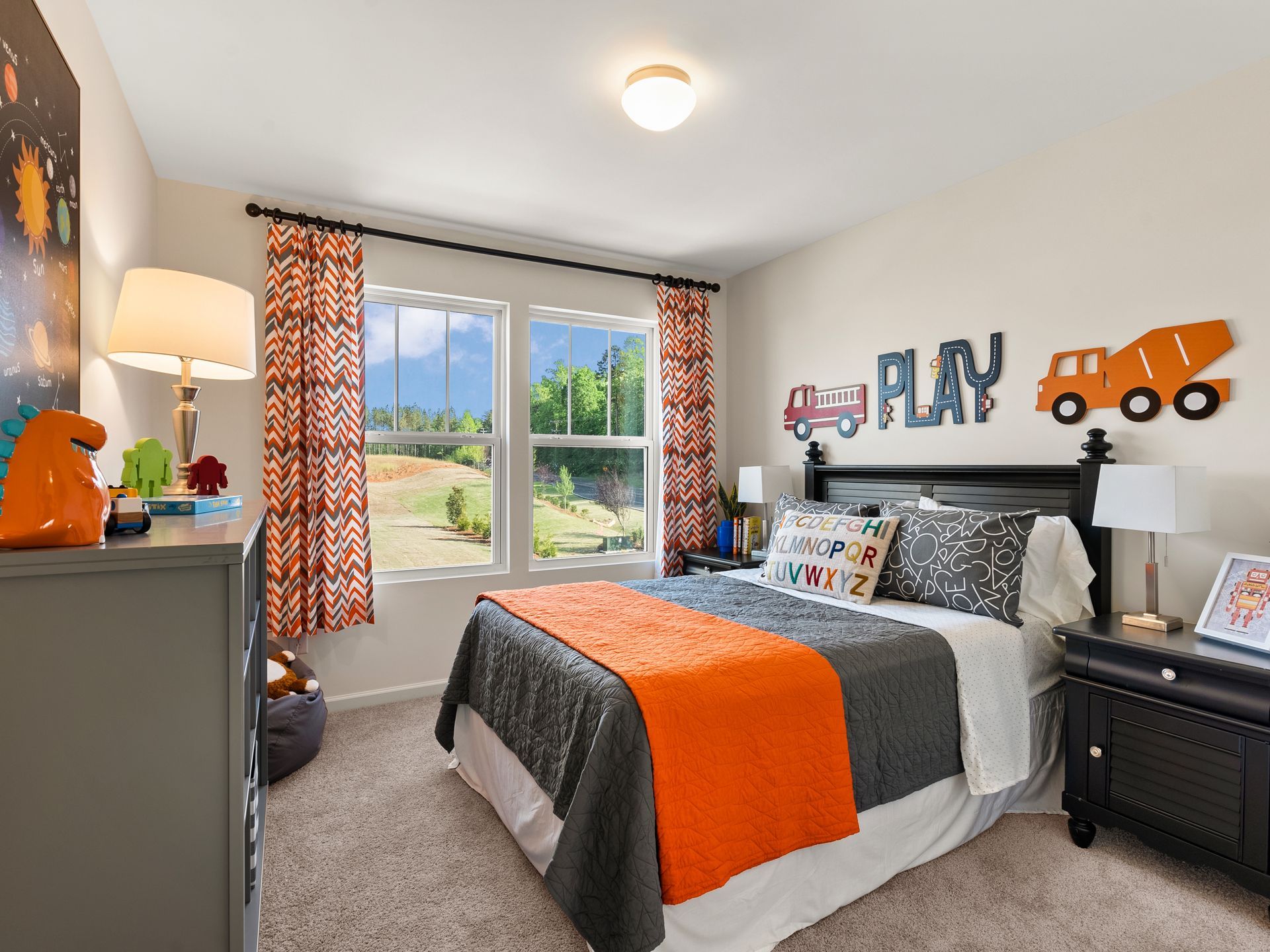 A bedroom with a bed , dresser , nightstand , and window.