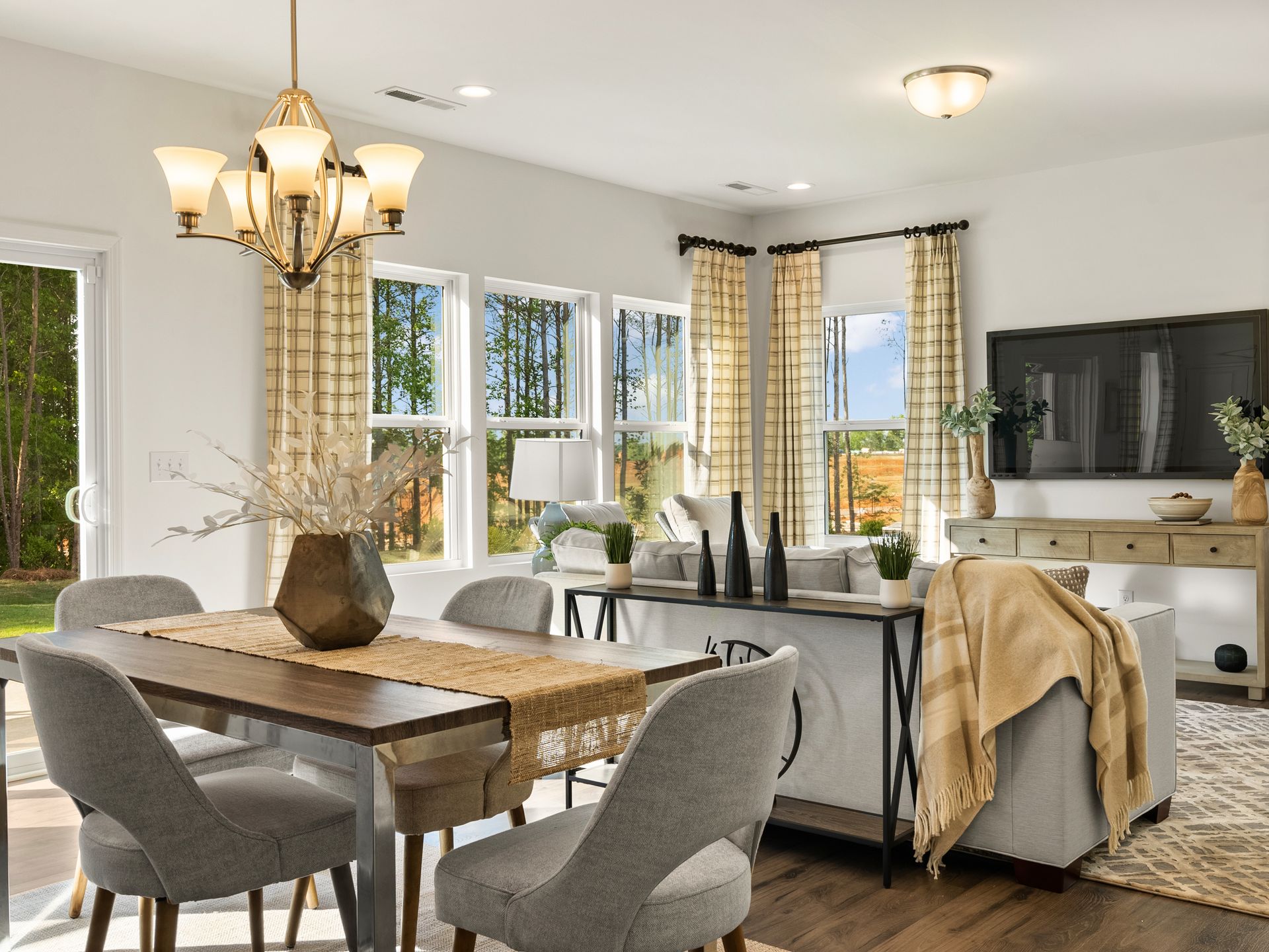 A living room with a dining table , chairs , a couch and a television.
