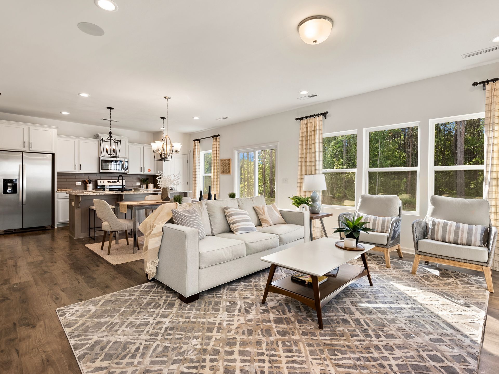 A living room with a couch , coffee table , chairs and a rug.
