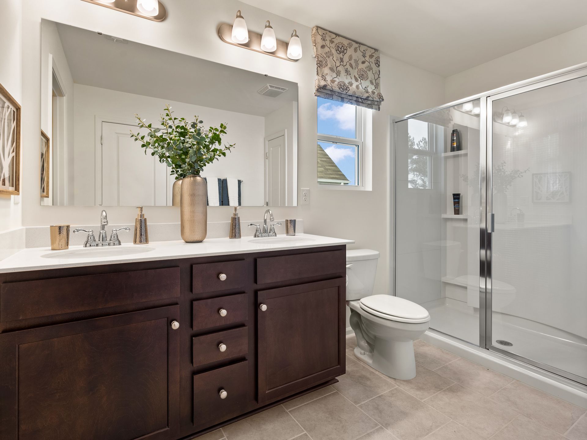 A bathroom with two sinks , a toilet , and a walk in shower.