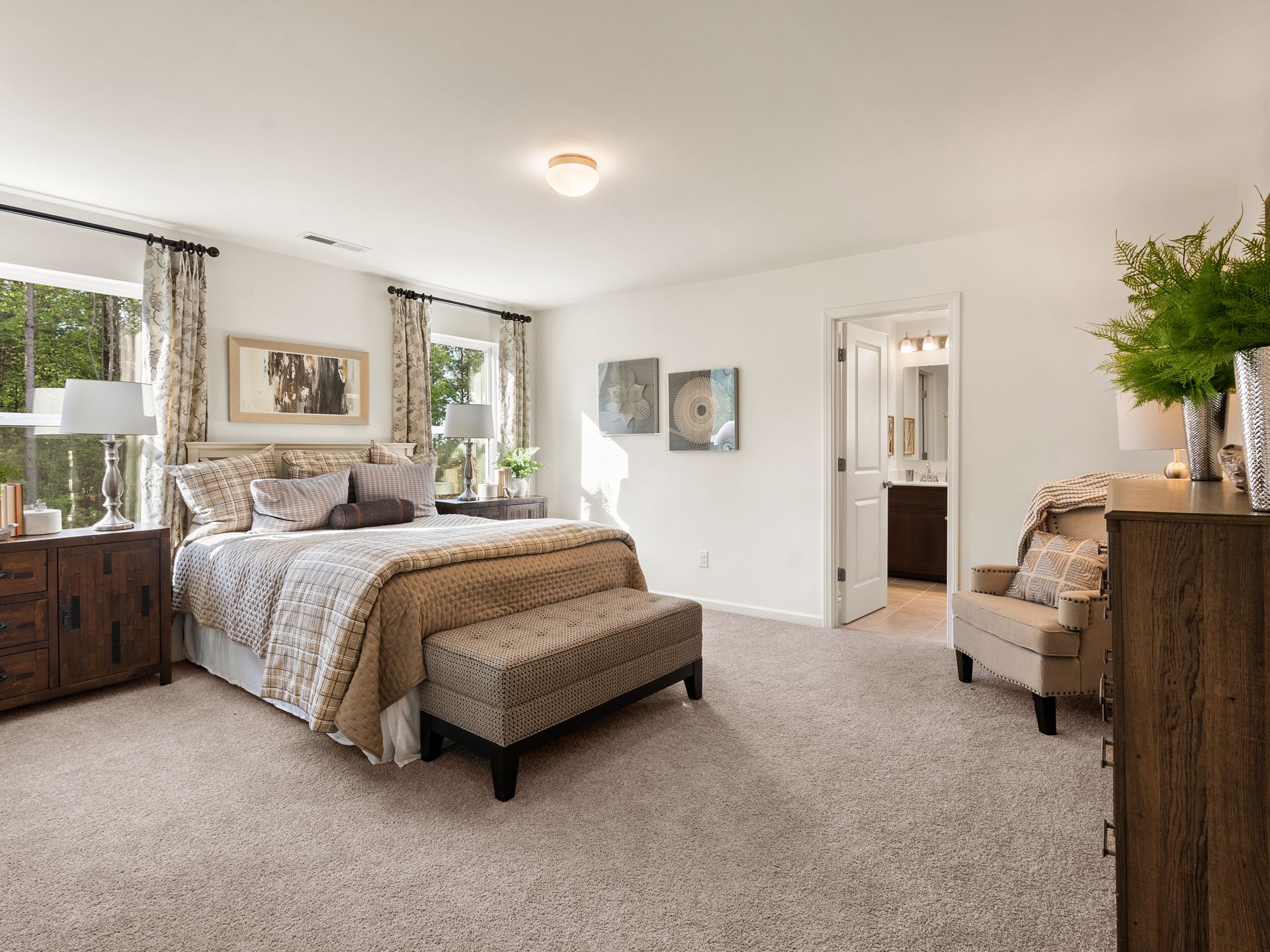 A bedroom with a bed , chair , dresser and window.