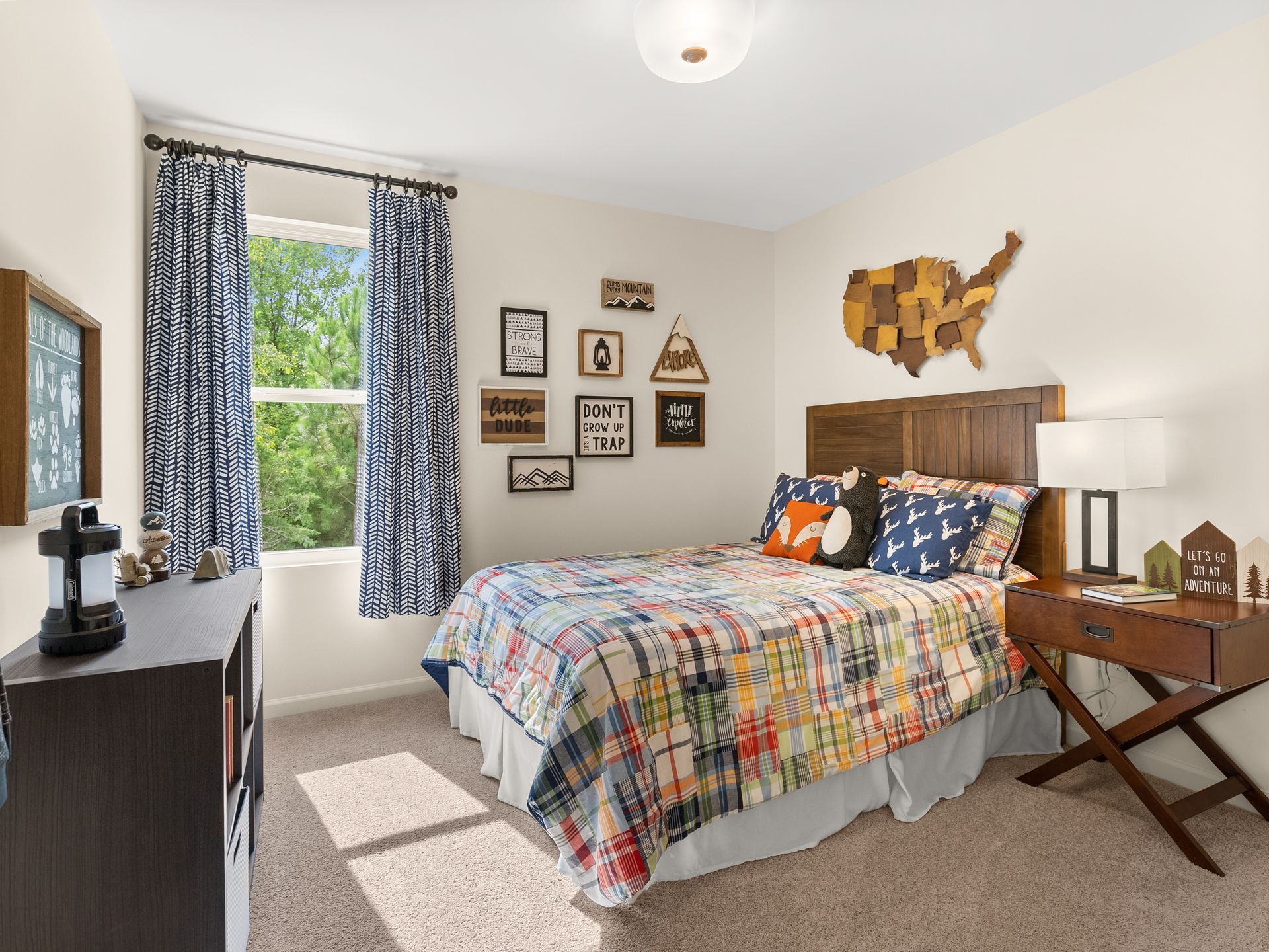 A bedroom with a bed , nightstand , dresser and window.