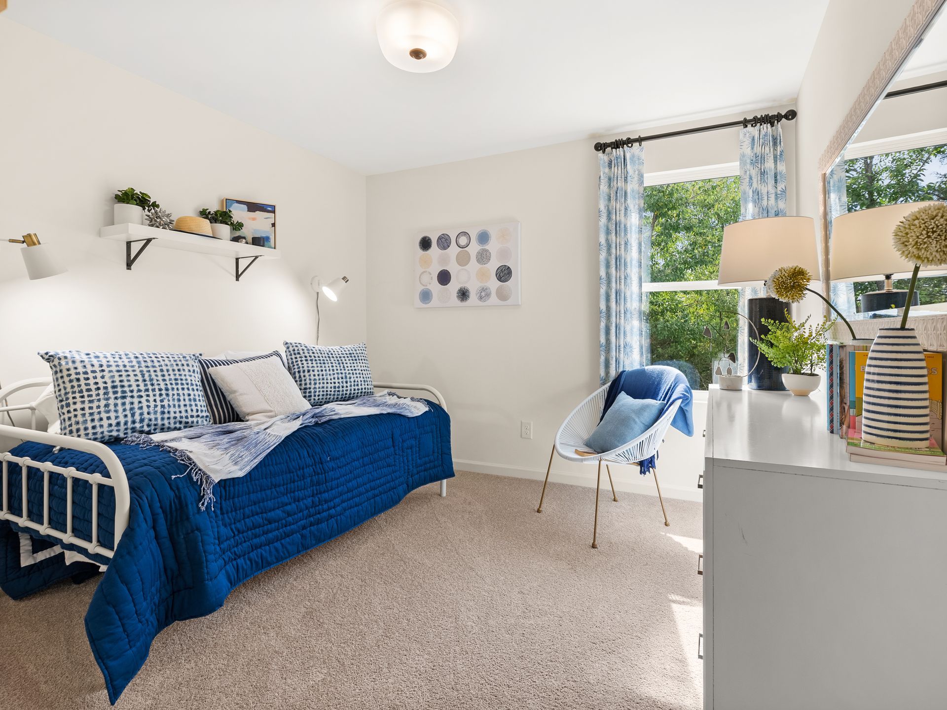A bedroom with a day bed , desk , chair and window.