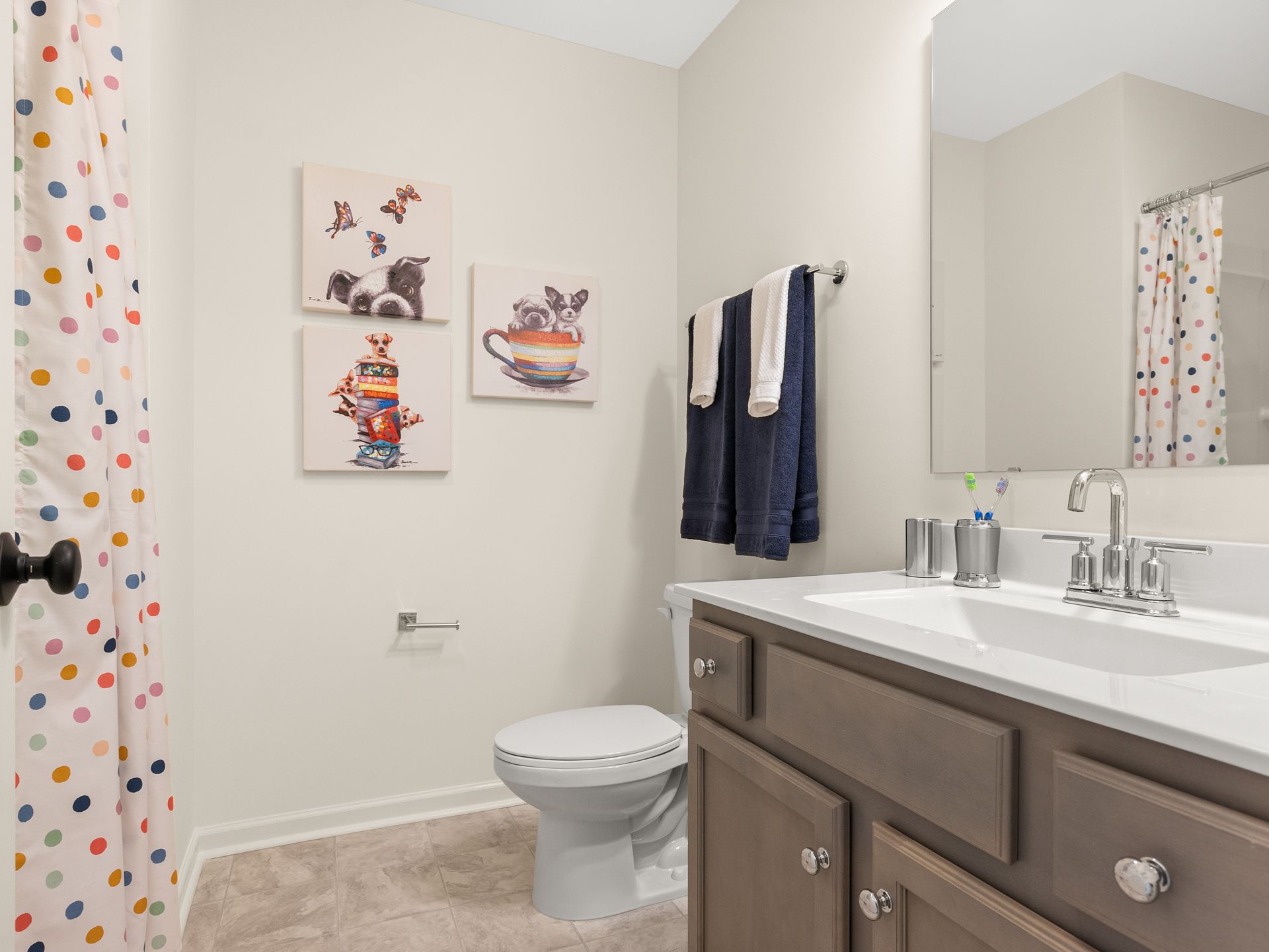 A bathroom with a toilet , sink , mirror and shower curtain.