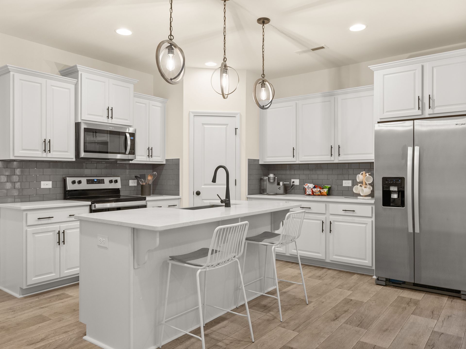 A kitchen with white cabinets , stainless steel appliances , and a large island.