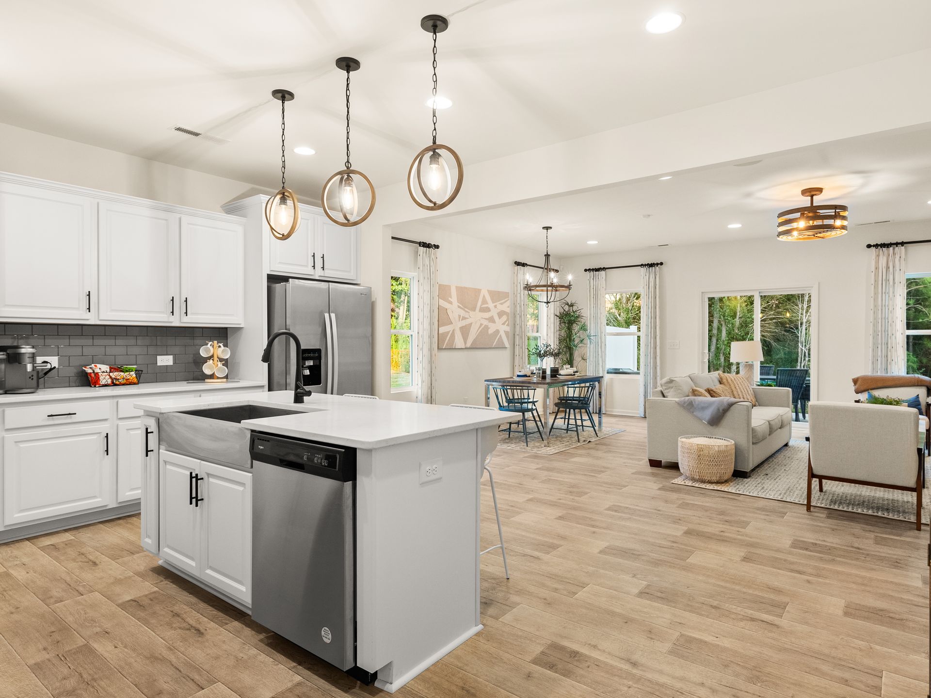 A kitchen with white cabinets and stainless steel appliances and a large island in the middle of the room.