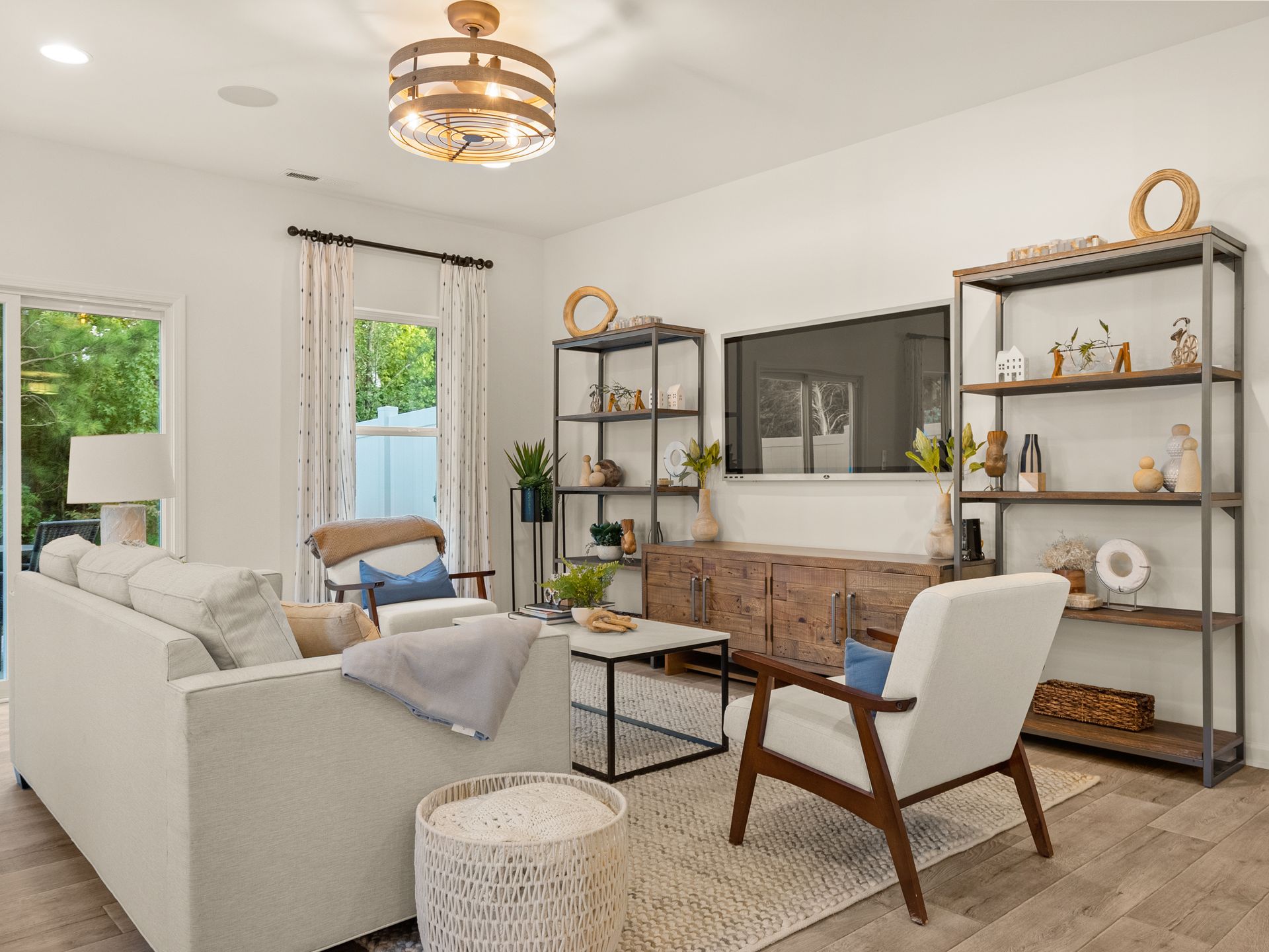 A living room with a couch , chairs , shelves and a flat screen tv.