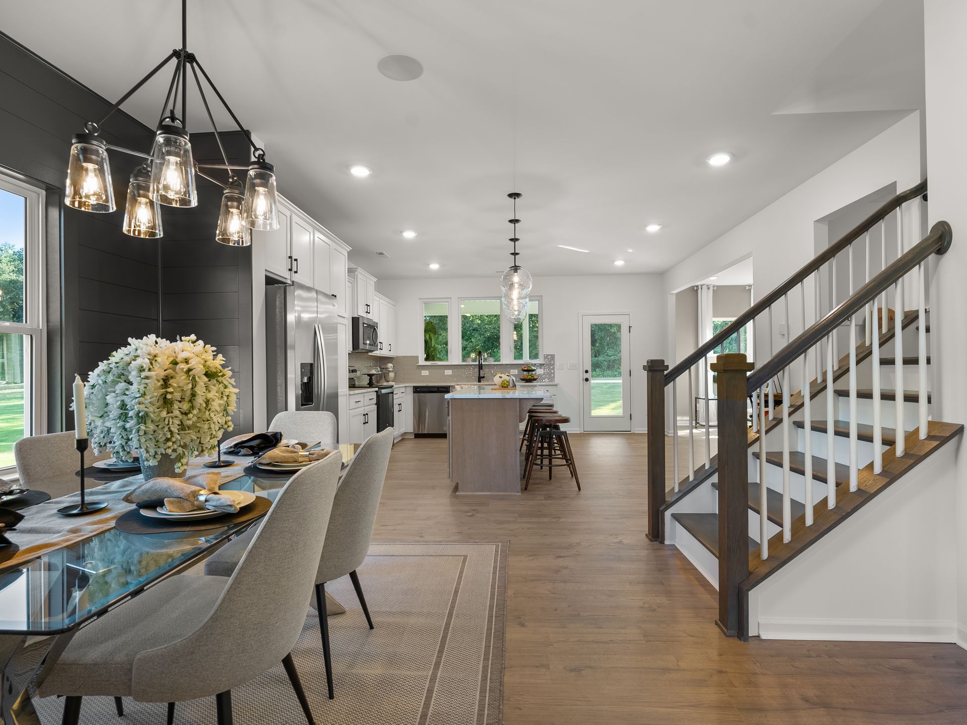 A dining room with a table and chairs and stairs leading to the kitchen.