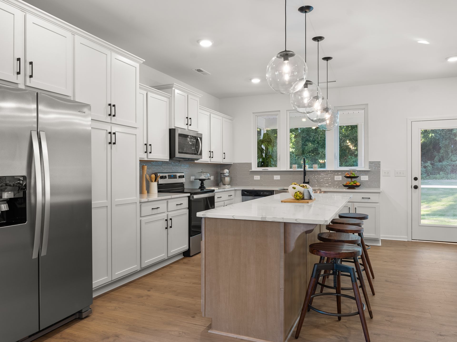 A kitchen with white cabinets , stainless steel appliances , and a large island.