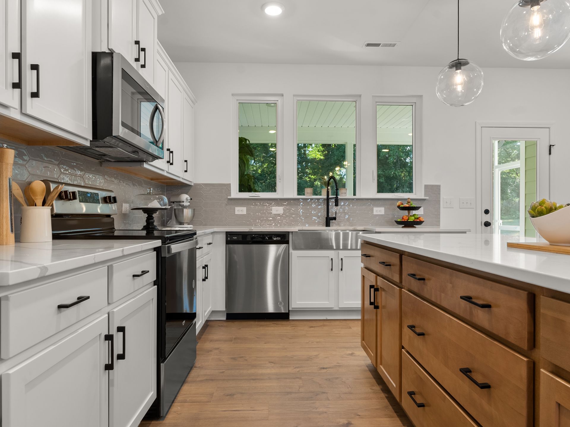 A kitchen with white cabinets , stainless steel appliances , a sink , and a large island.