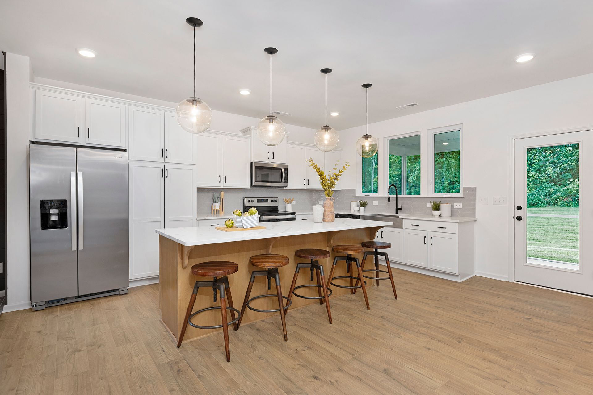 A kitchen with a large island , stools and a refrigerator.