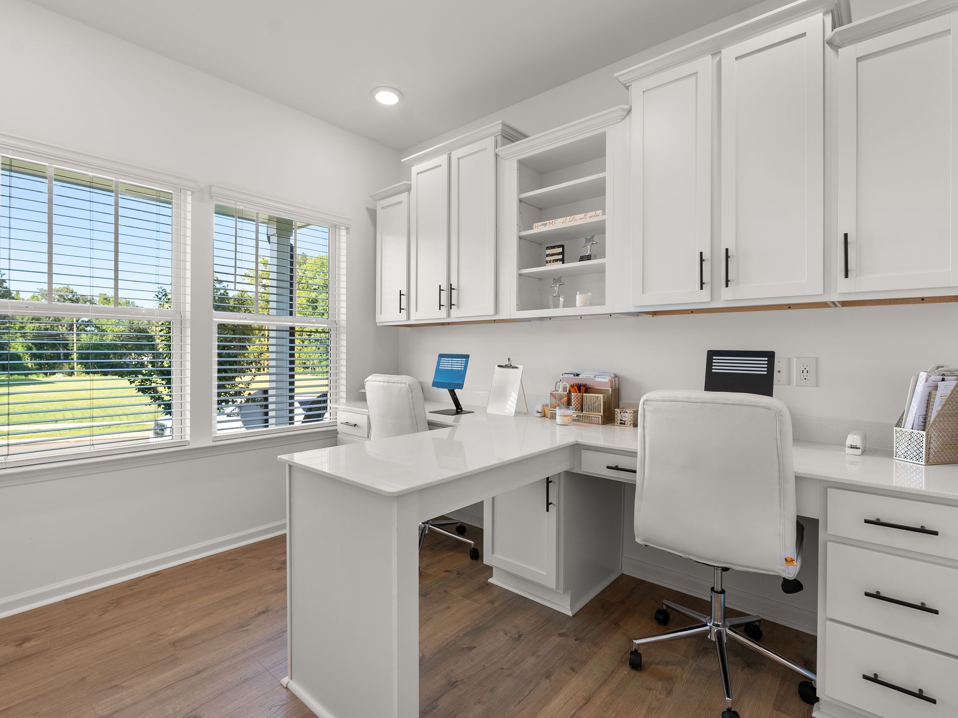 A home office with white cabinets , a desk and a chair.