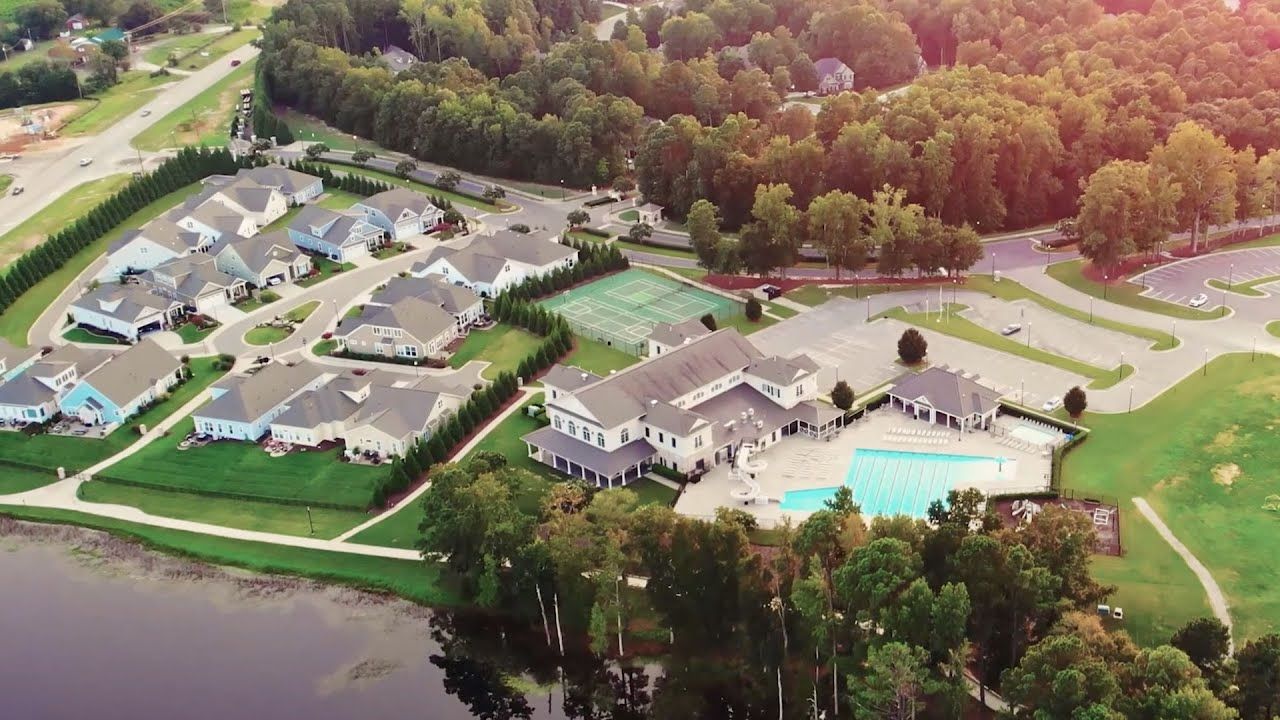 An aerial view of a residential area with a lake and a swimming pool.