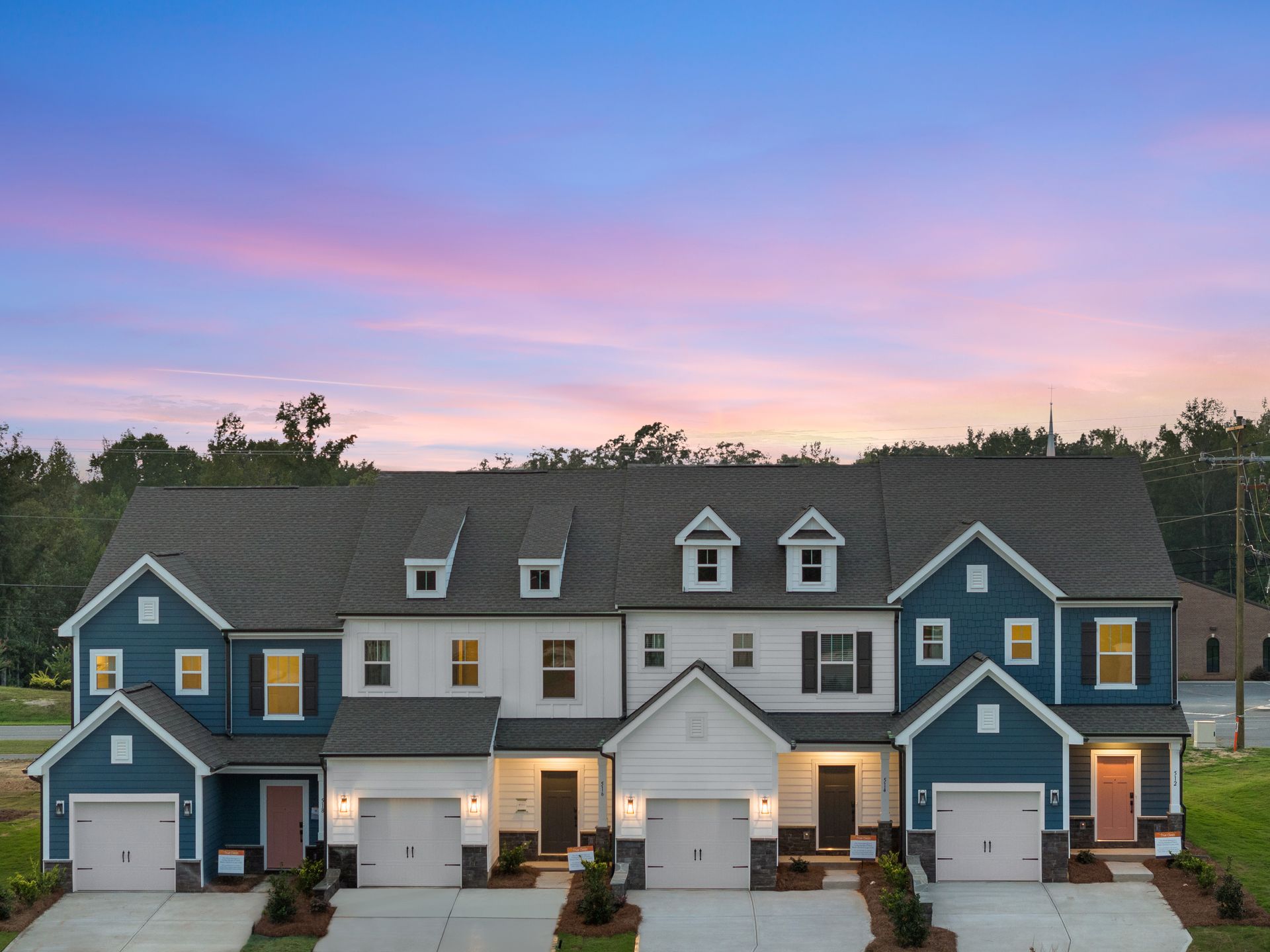 A row of blue and white houses with a sunset in the background.