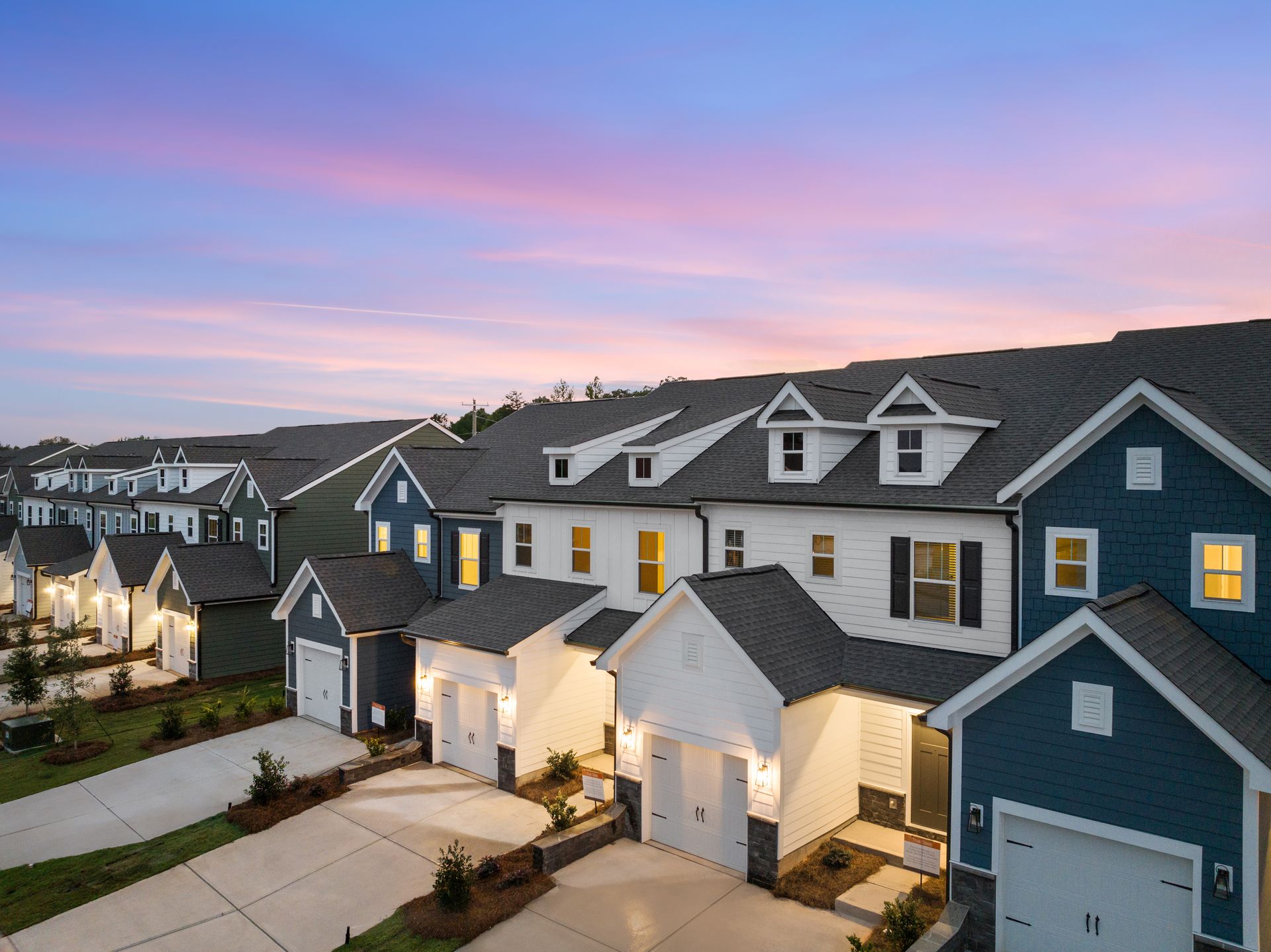 A row of blue and white houses with a sunset in the background.