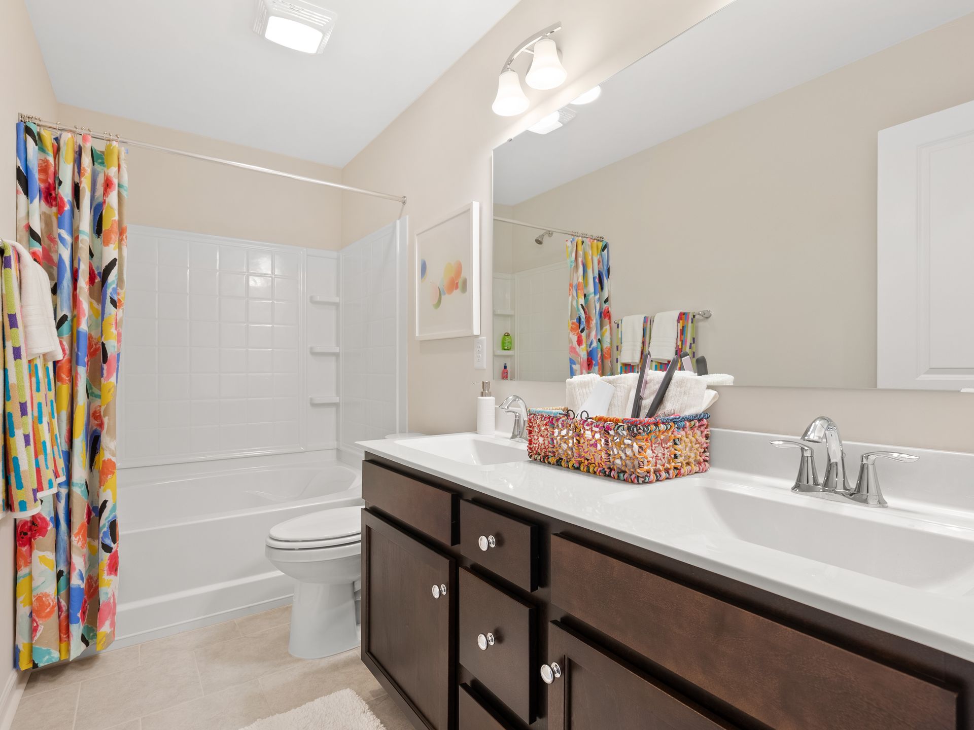 A bathroom with a sink , toilet , shower and mirror.