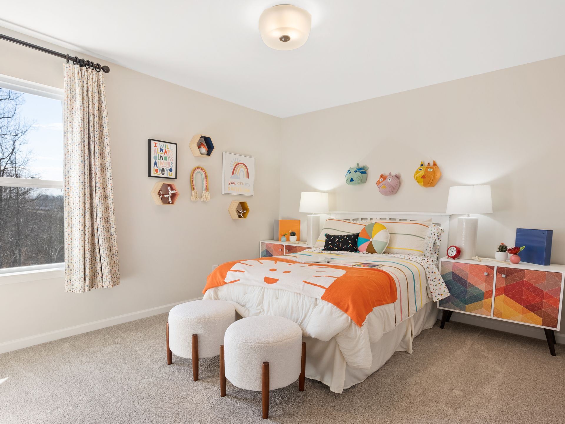 A bedroom with a bed , two ottomans and a window.