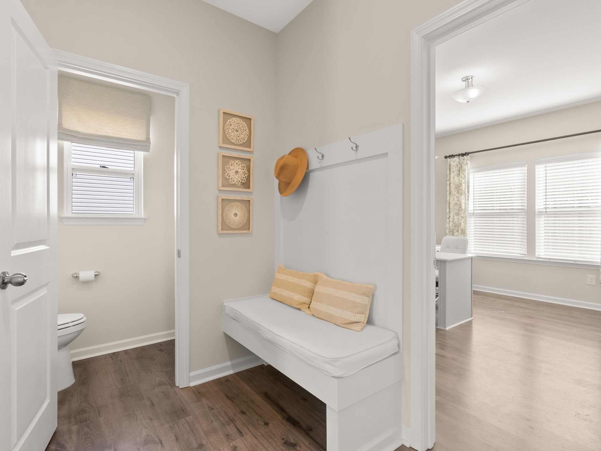 A hallway with a bench and a hat hanging on a hook.