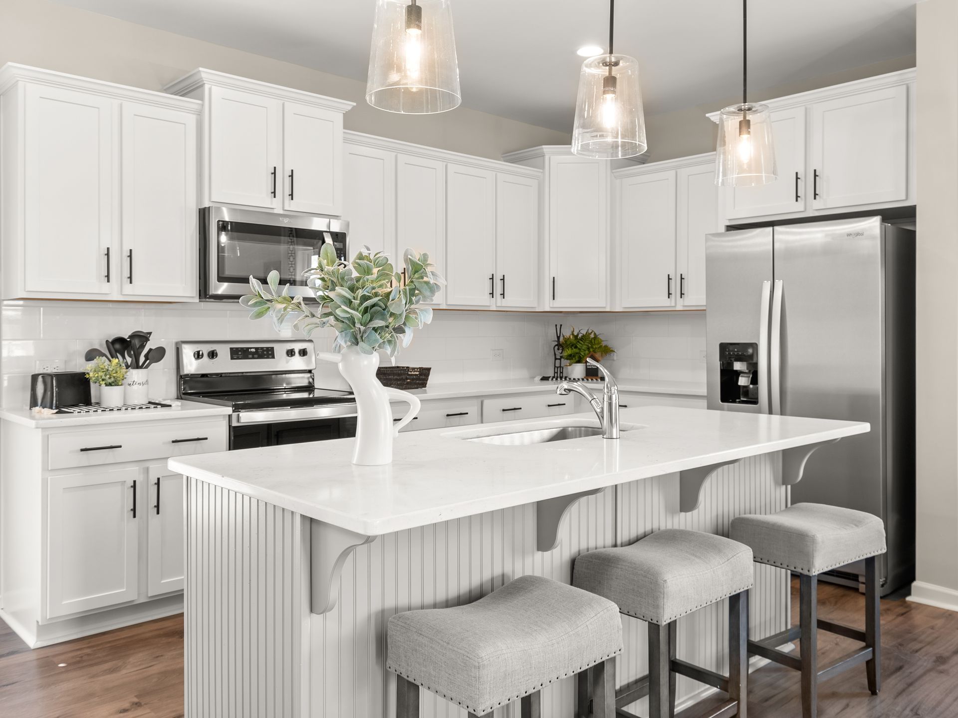 A kitchen with white cabinets , stainless steel appliances , and a large island.
