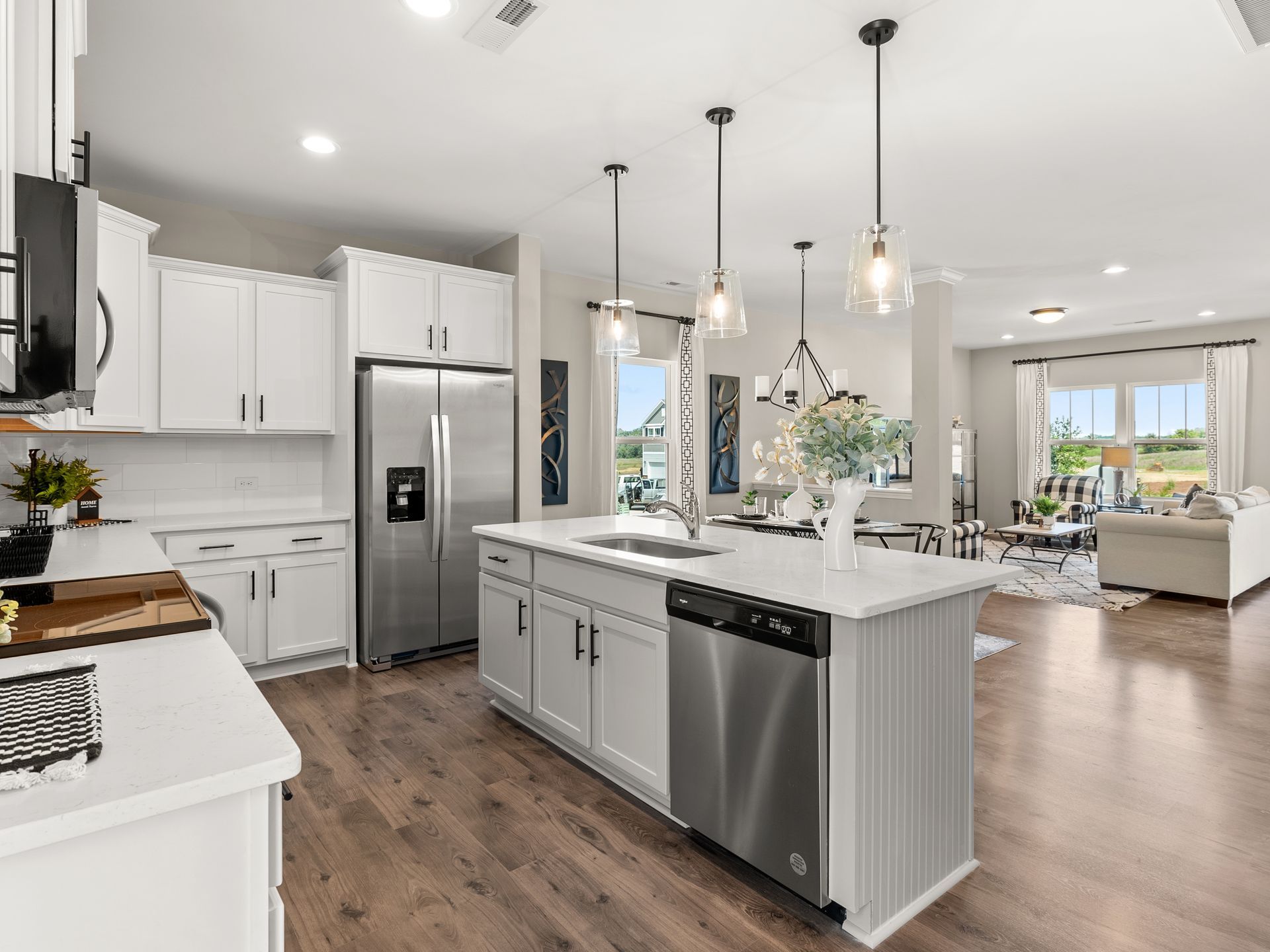 A kitchen with white cabinets , stainless steel appliances , and a large island.