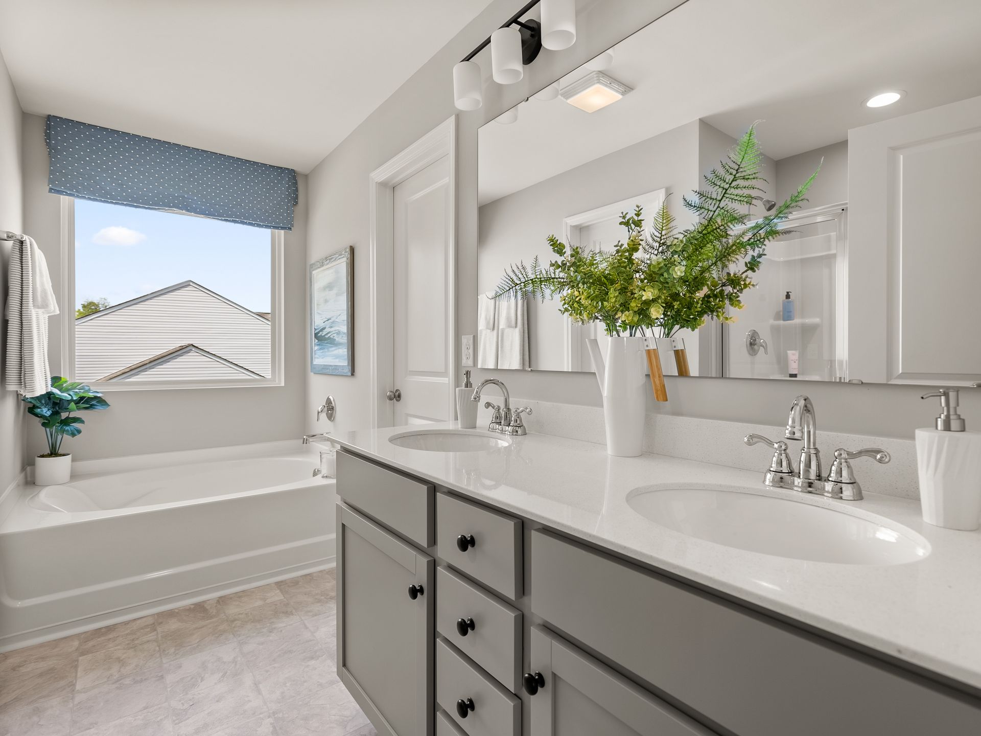 A bathroom with two sinks , a tub , and a large mirror.