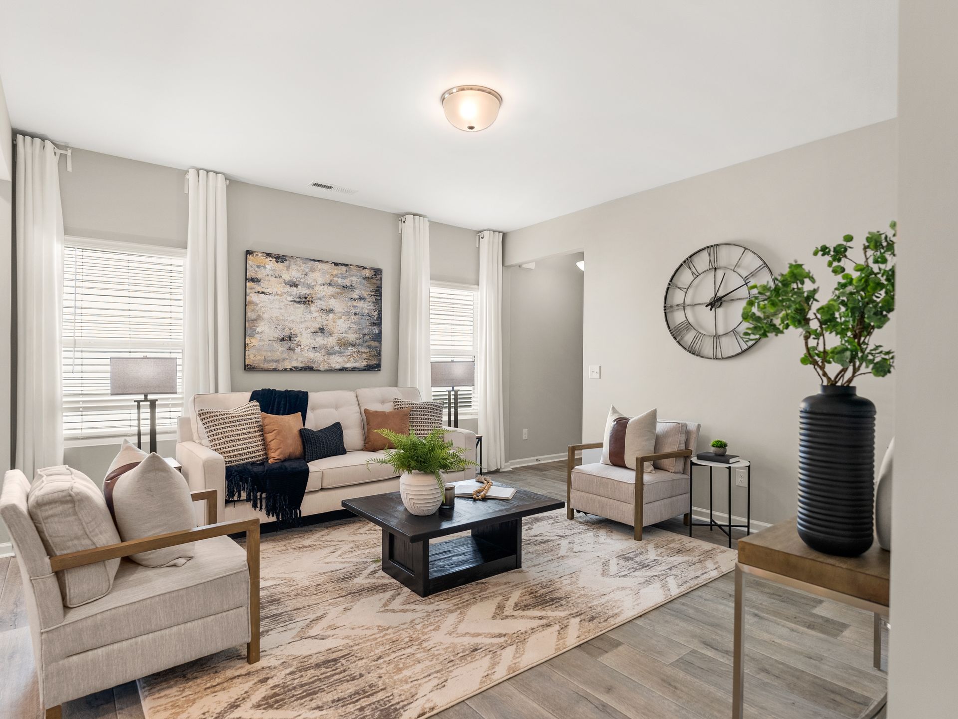 A living room with a couch , chairs , coffee table and a clock on the wall.