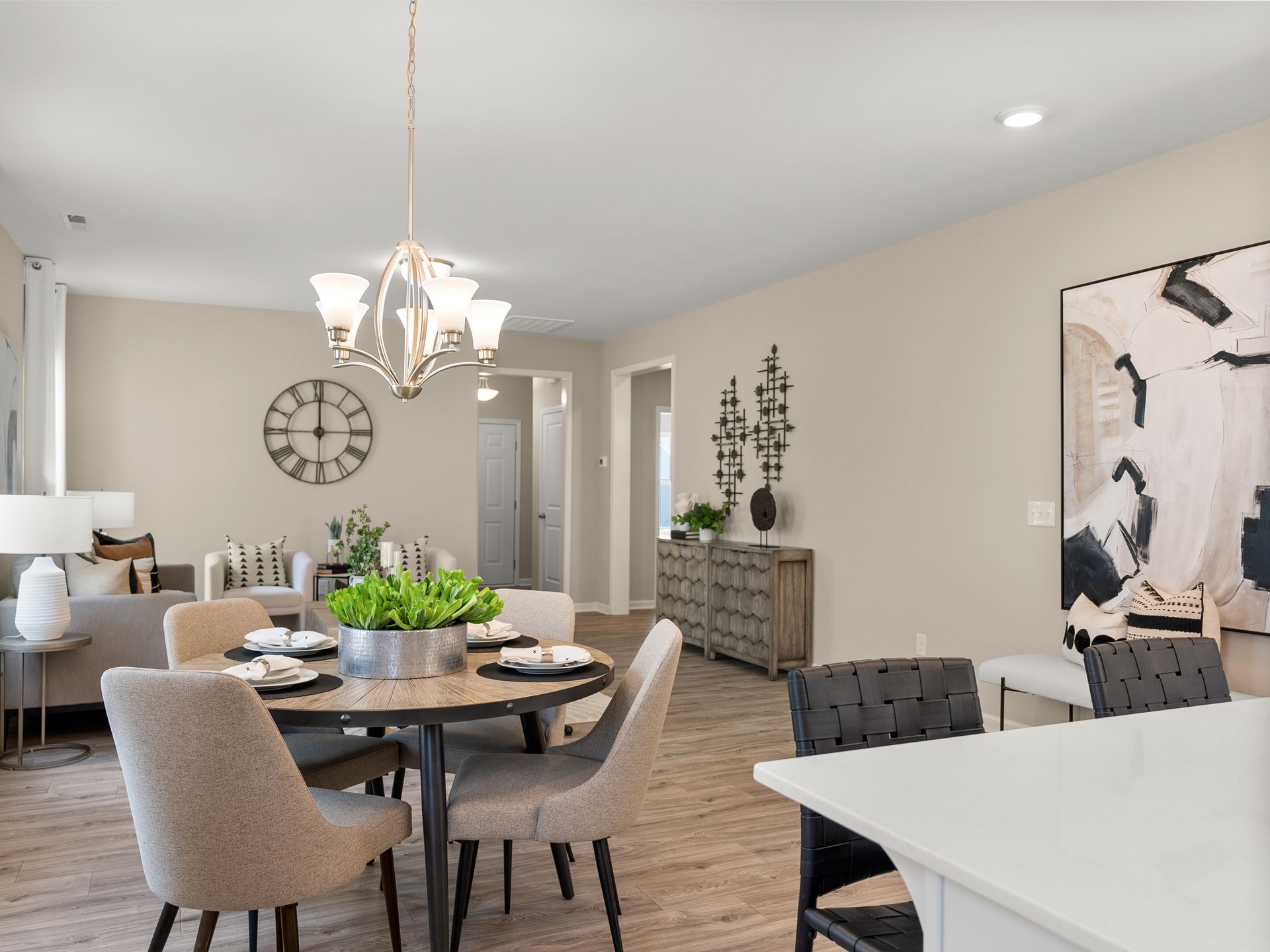 A dining room with a table and chairs and a clock on the wall.