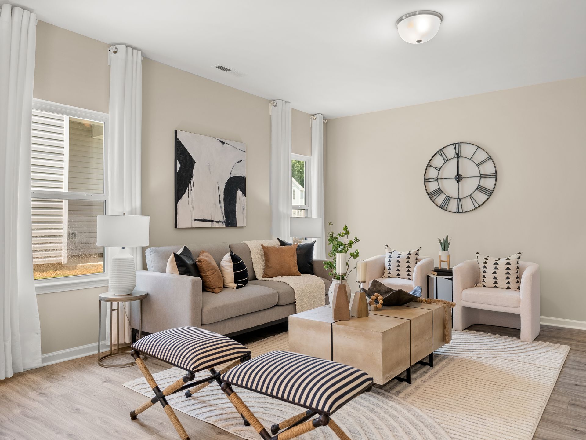 A living room with a couch , chairs , coffee table and a clock on the wall.