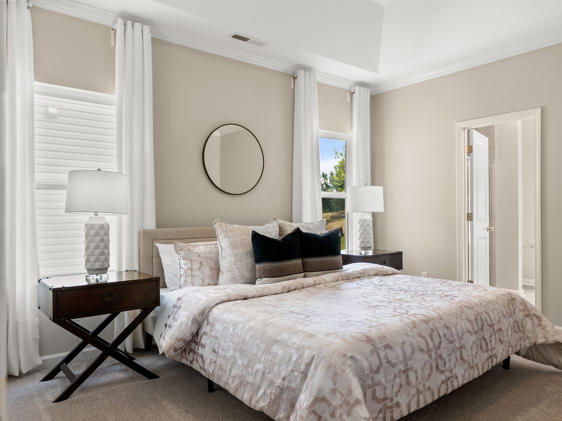 A bedroom with a king size bed , nightstands , lamps and a mirror.