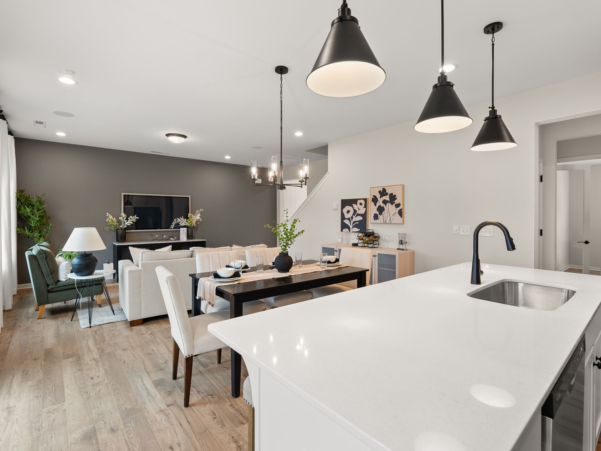 A kitchen with a sink , dining table and chairs in a living room.