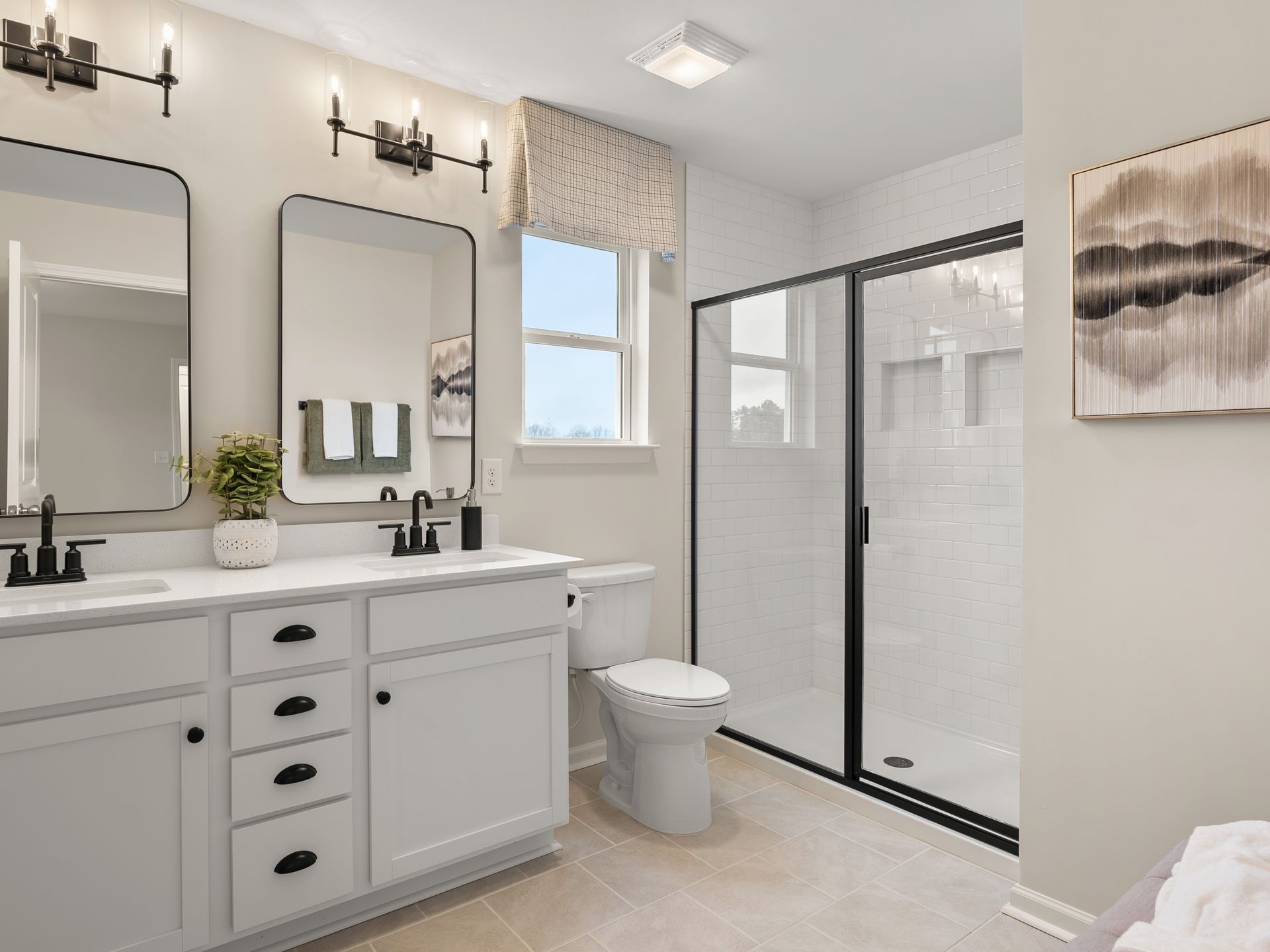 A bathroom with two sinks , a toilet , and a walk in shower.