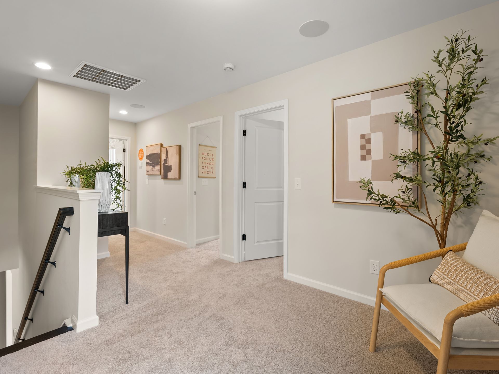 A living room with a chair , stairs and a painting on the wall.