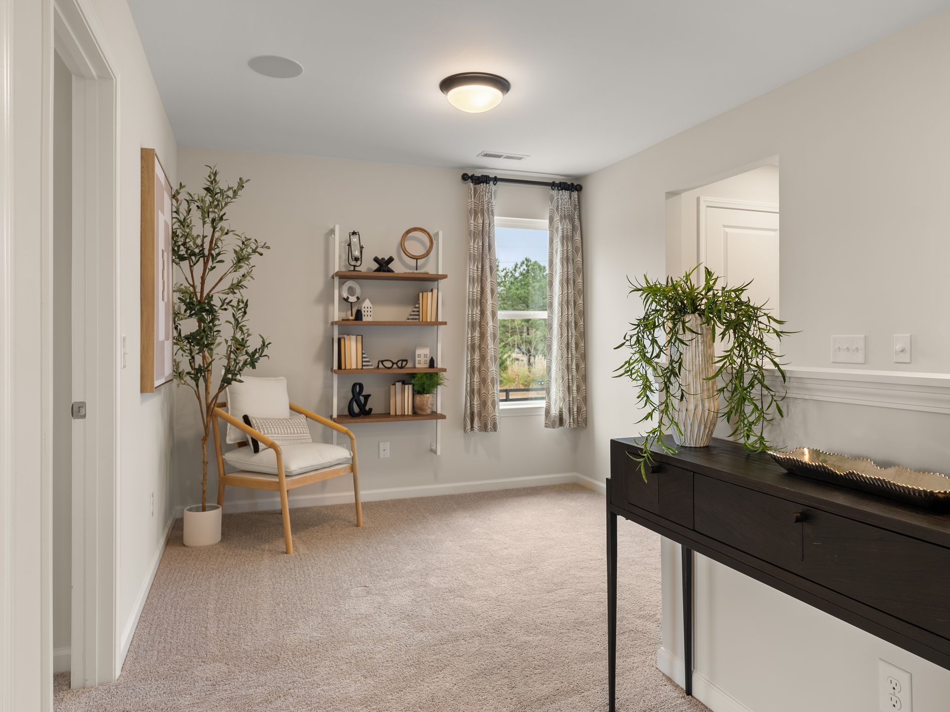 A living room with a chair , table , shelves and a window.