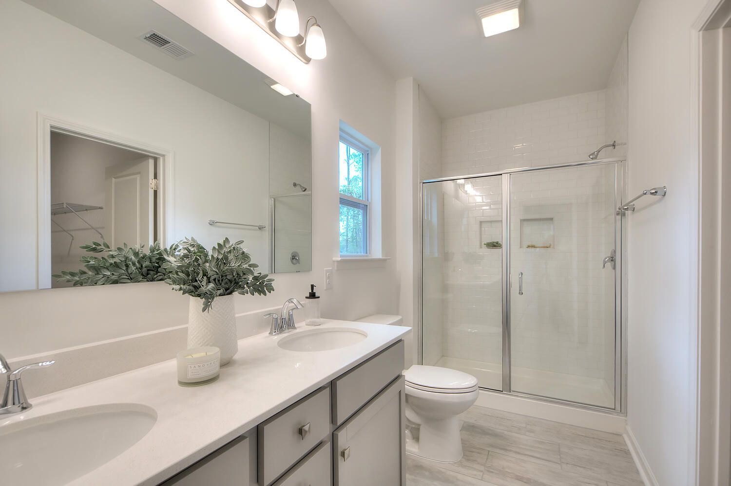 A bathroom with two sinks , a toilet , and a walk in shower.