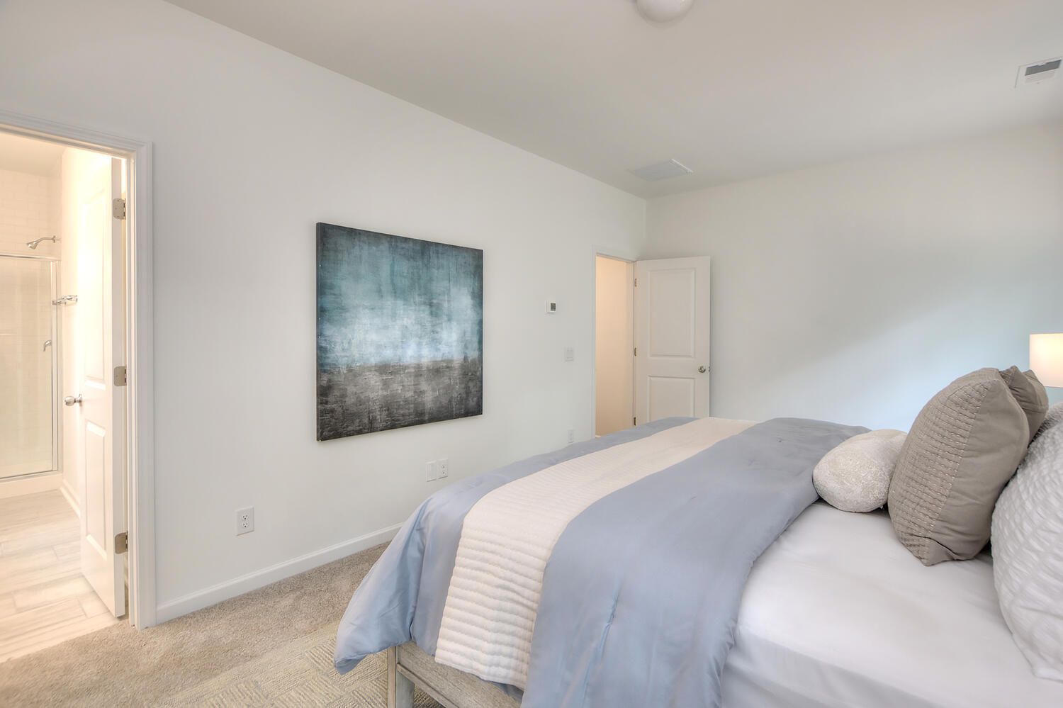 A bedroom with a large bed and a painting on the wall.