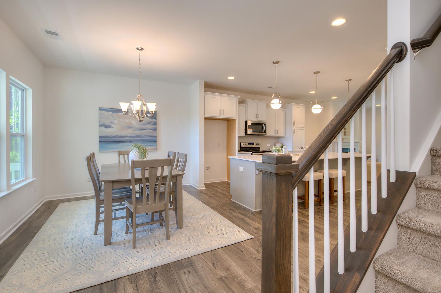 A dining room with a table and chairs and stairs leading to the kitchen.