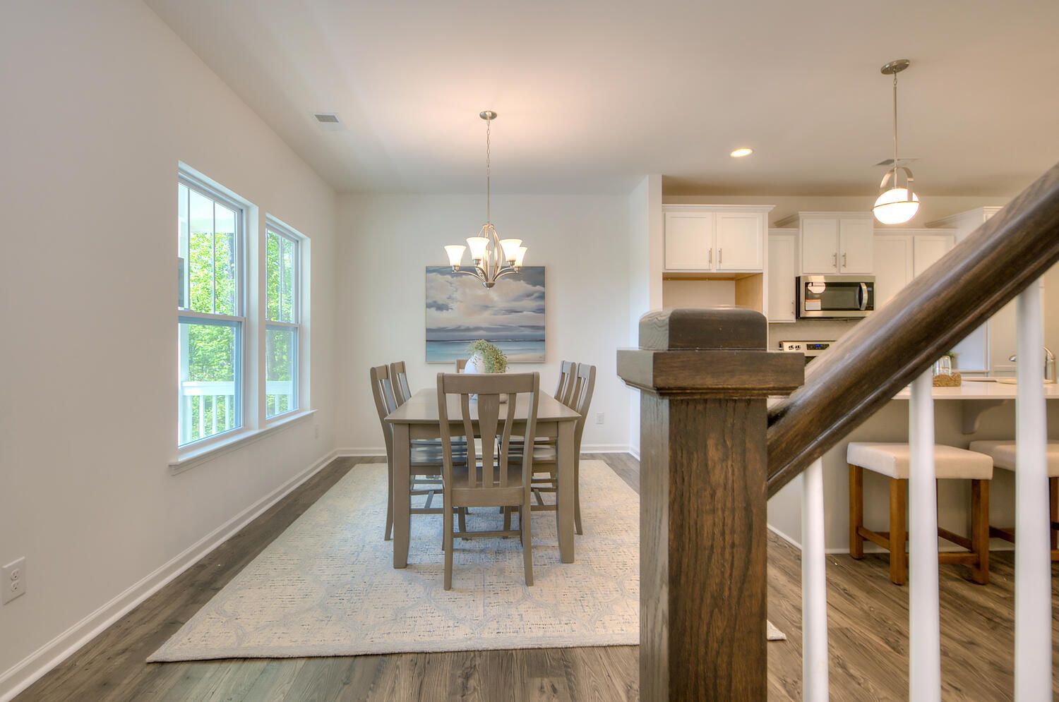 A dining room with a table and chairs and a staircase leading to the kitchen.