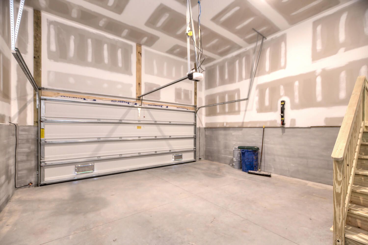 An empty garage with a garage door open and a staircase.