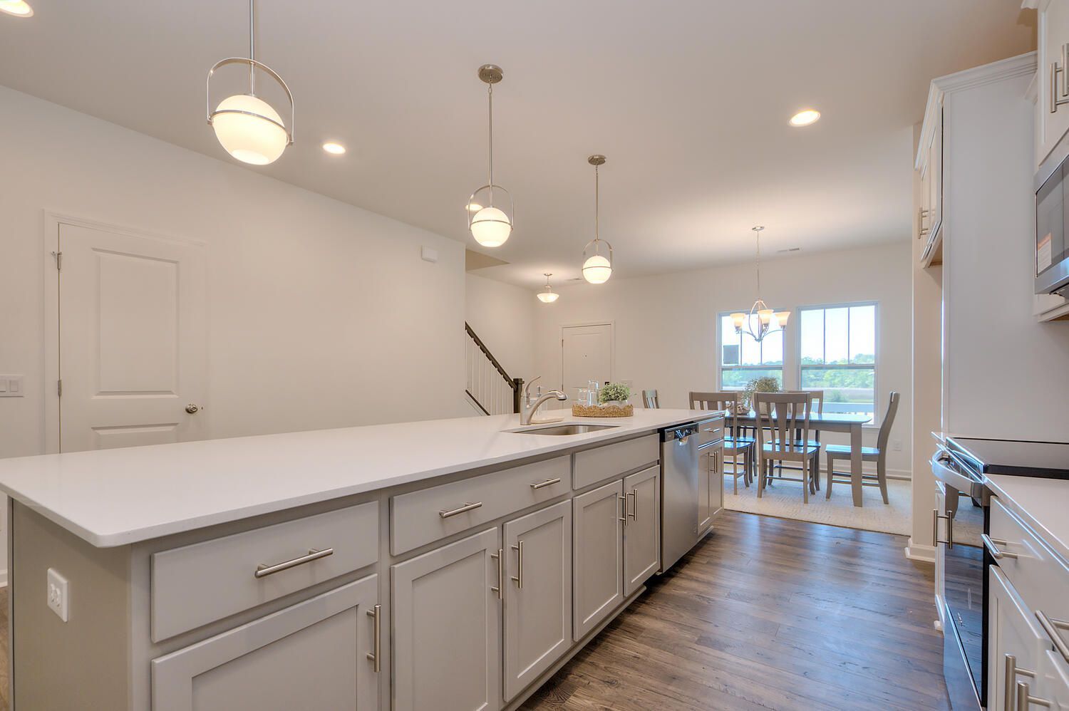 A kitchen with white cabinets , stainless steel appliances , and a large island.