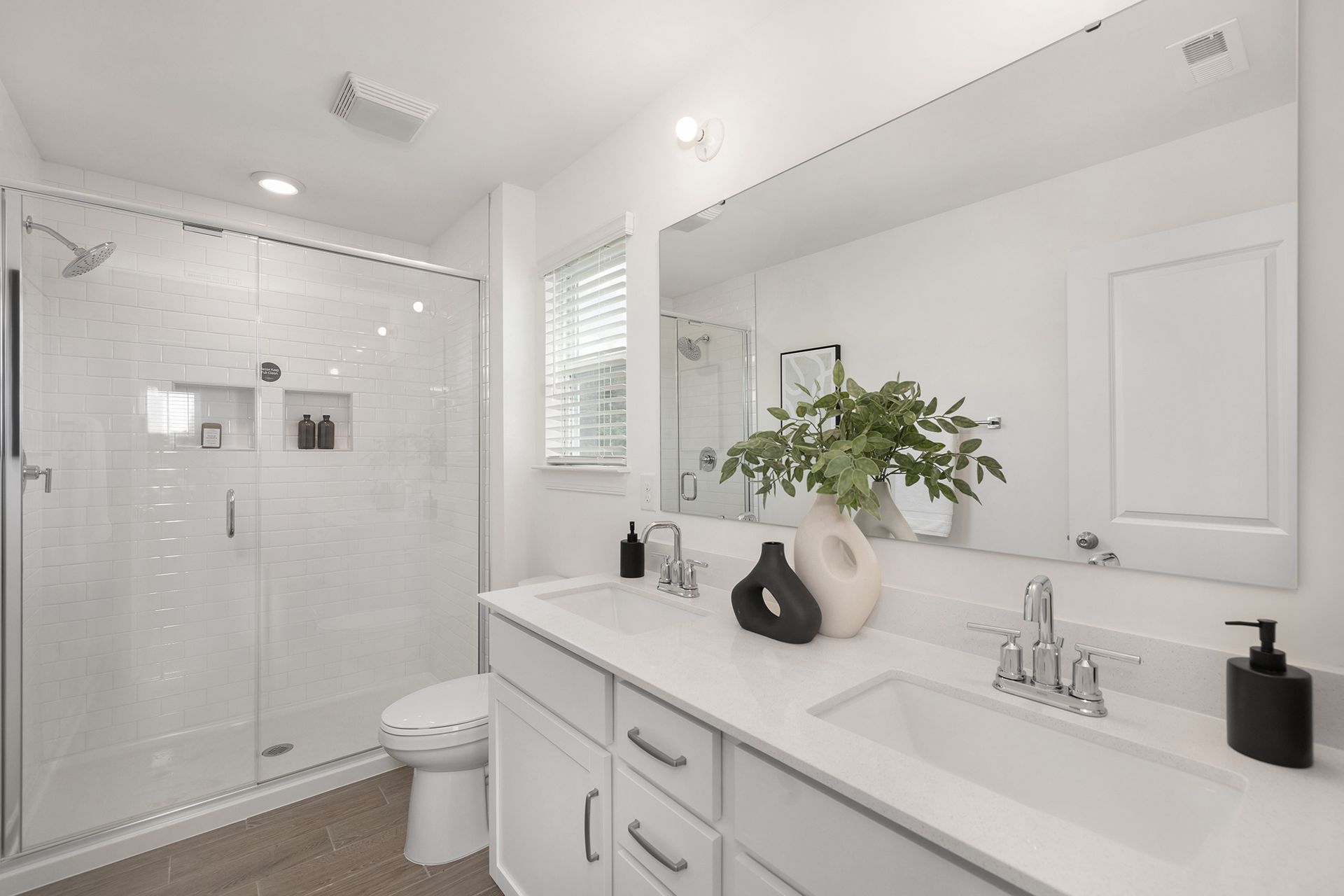 A bathroom with a toilet , sink , mirror and shower.